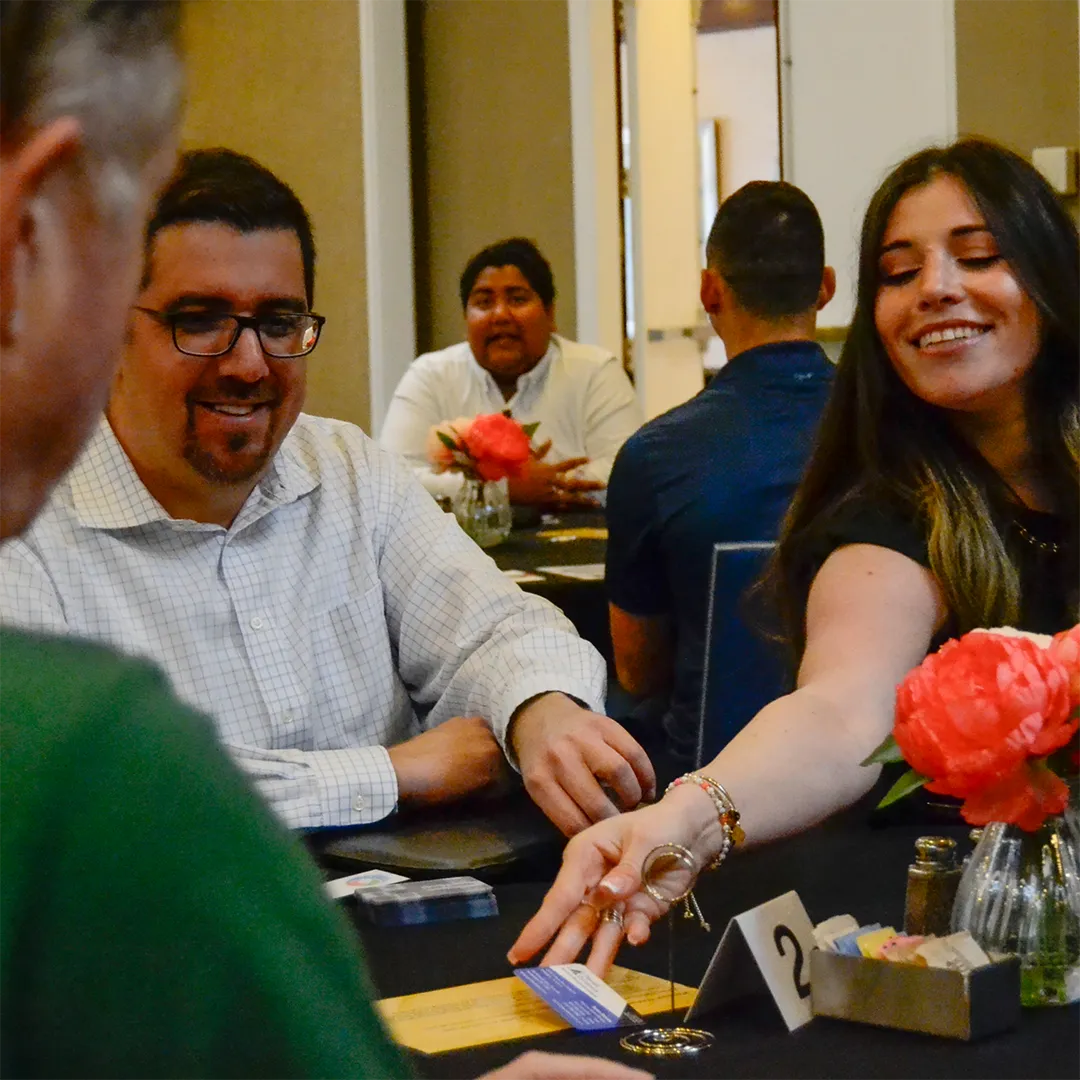 Man and woman shake hands at a table while engaging in a friendly game.