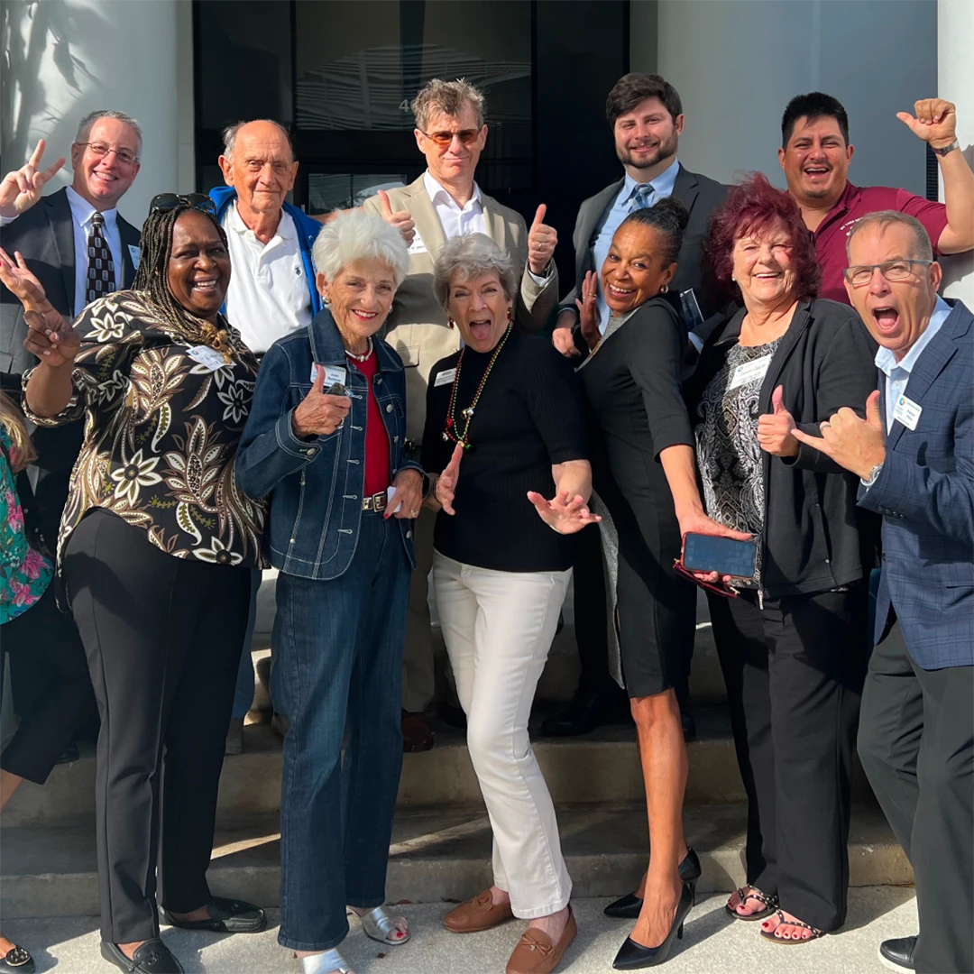 Group of smiling people posing together for a photo outdoors.