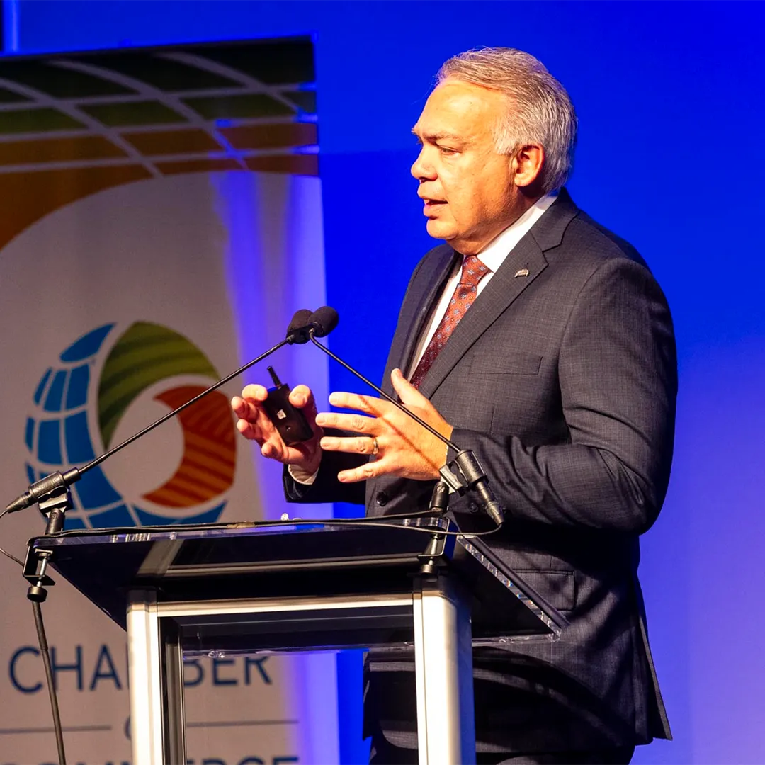 Man wearing a suit and tie speaks confidently at a podium.